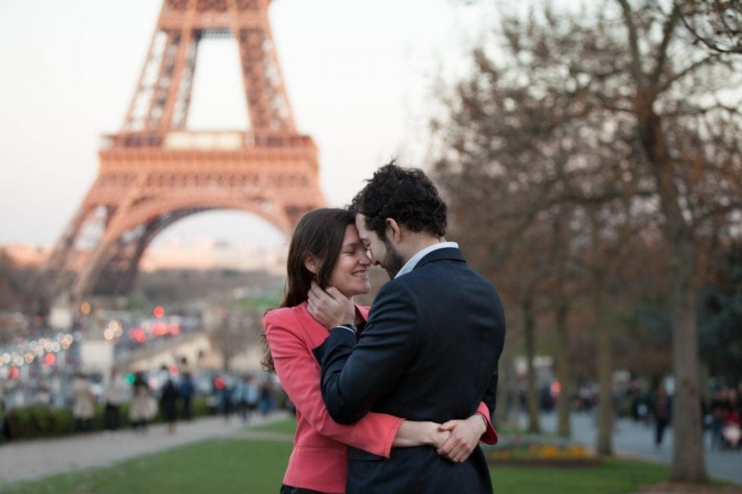 Couple cuddling in front of the Eiffel Tower