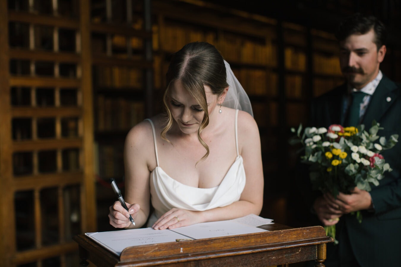 Handwritten vows placed gently atop an open book inside Oxford’s Duke Humfrey’s Library