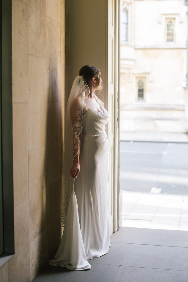 The bride stands alone in front of the Old Bank Hotel, a calm moment before the ceremony