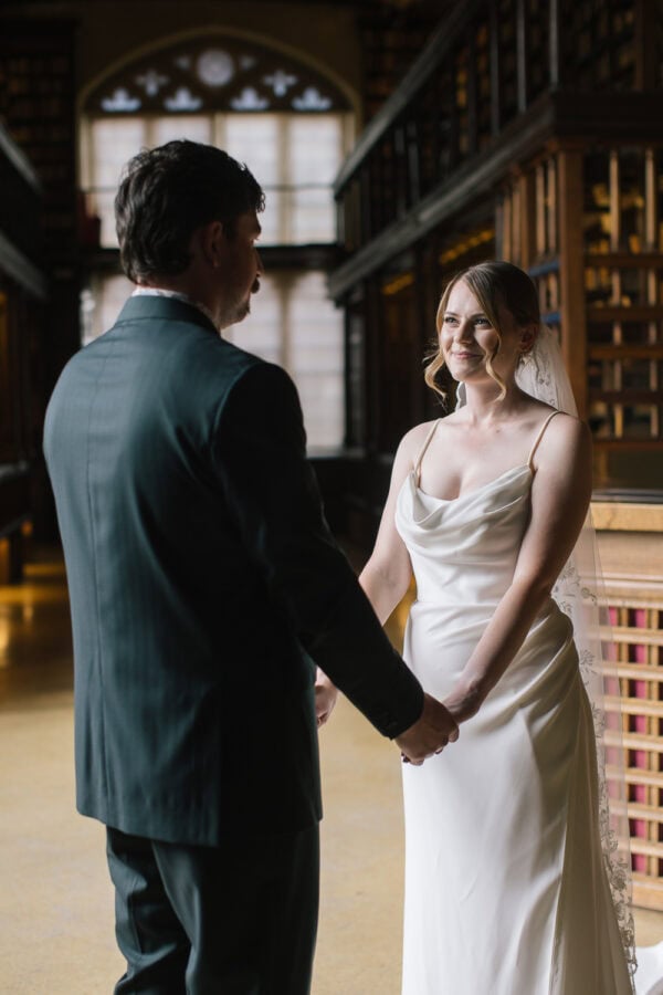 Modern couple holding hands in the heart of the Bodleian Library, with Duke Humfrey’s Library as their ceremony backdrop