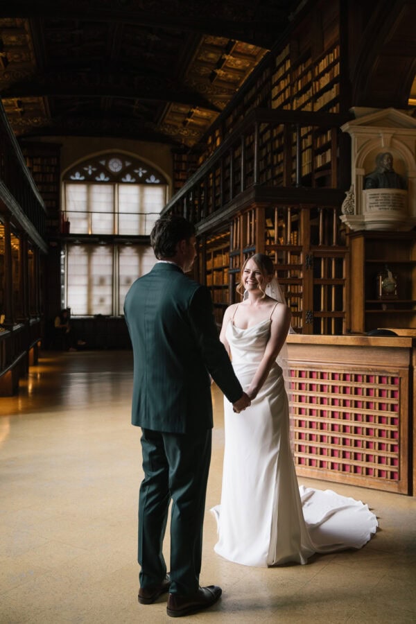 Editorial-style portrait of the couple inside the historic Duke Humfrey’s Library, Oxford’s oldest reading room